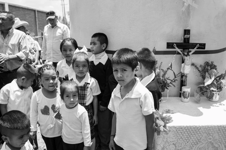 a group of children are standing outside by a cross