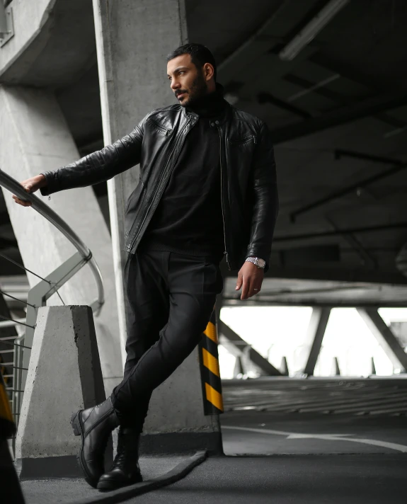 a man posing on the ground in black clothes and boots