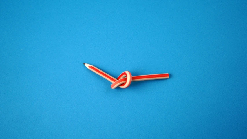 a red scissors that is sticking into some blue paper