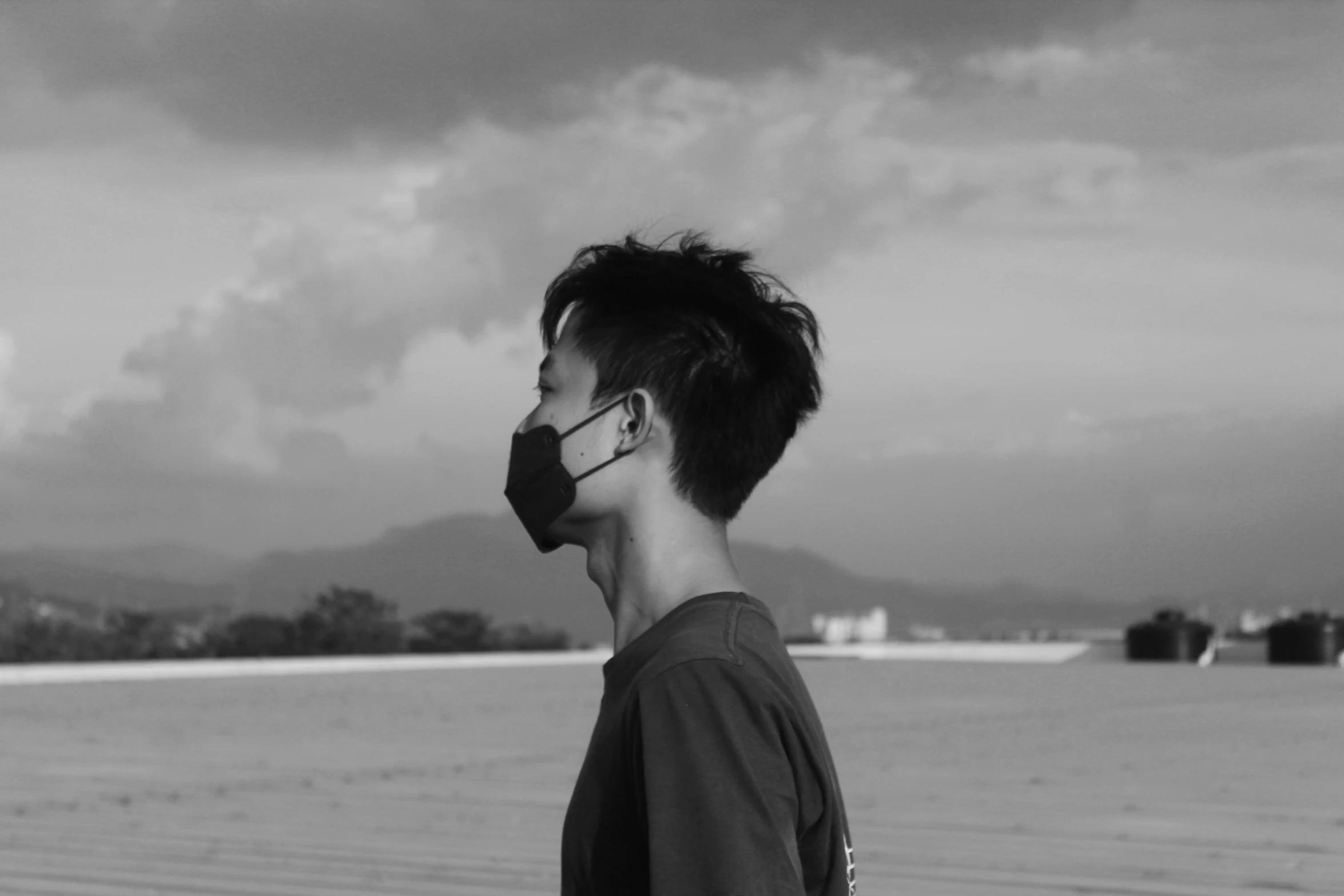 a man standing near an ocean under a cloudy sky