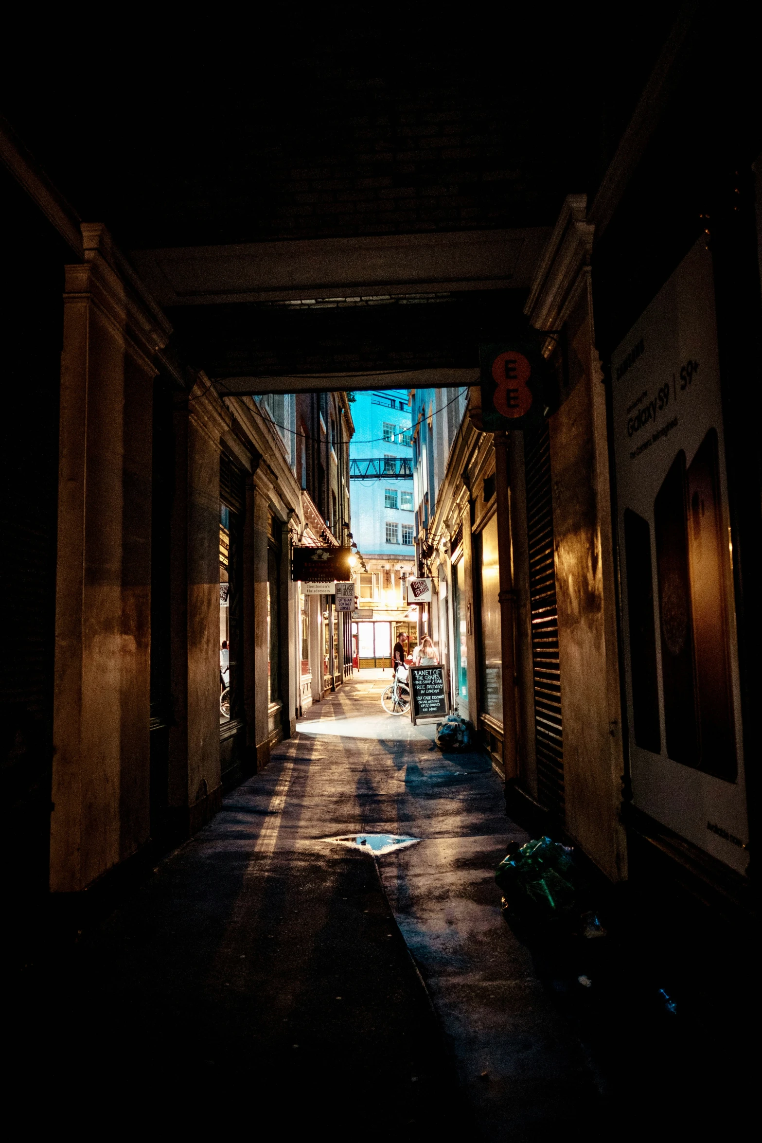 an empty dark city street lined with shops and restaurants