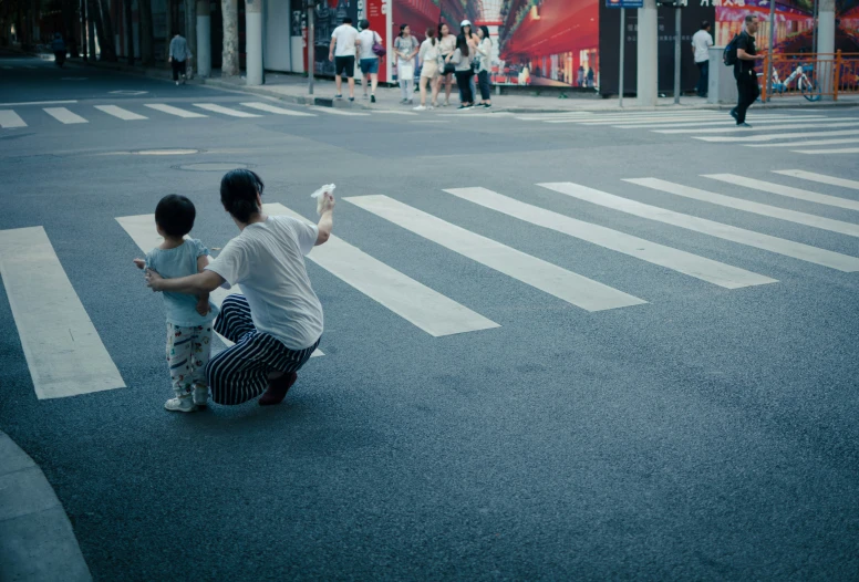 a man is sitting on the sidewalk next to a little boy