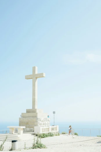 a woman standing near a very big white cross
