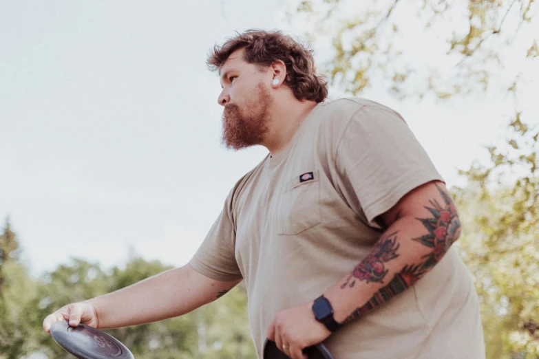 a man wearing a tan shirt and some tattoos