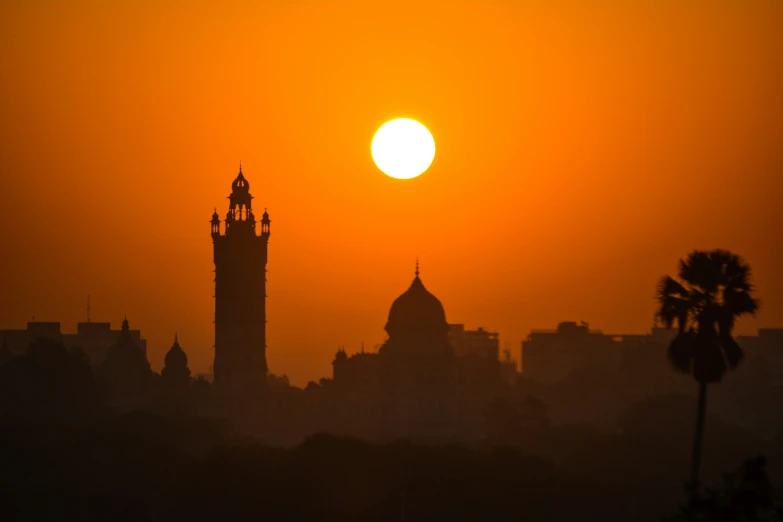 the sun is setting over the large tower of a building