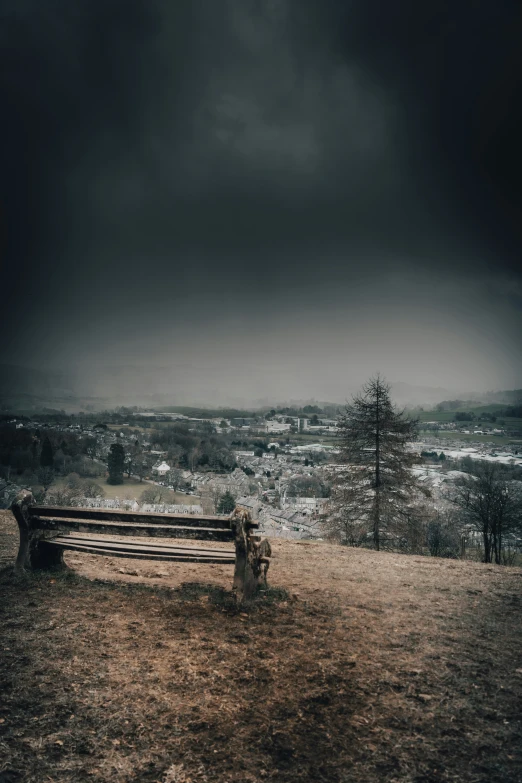 an abandoned bench on a hill with a gloomy sky