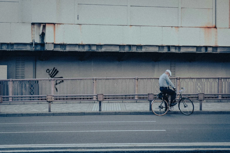 a man riding his bicycle down a street near a wall