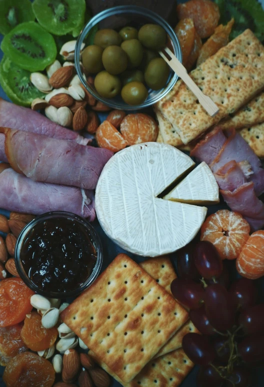 a cheese board with fruits and ers next to a knife