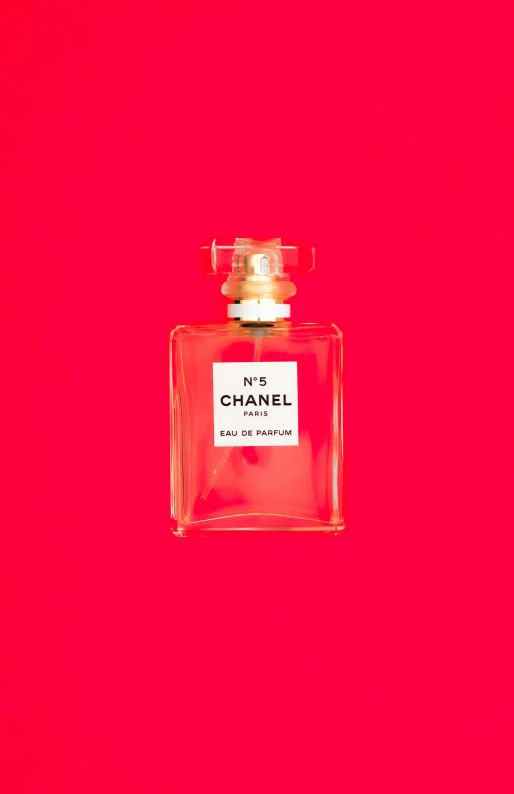 the front of a perfume bottle on a pink background