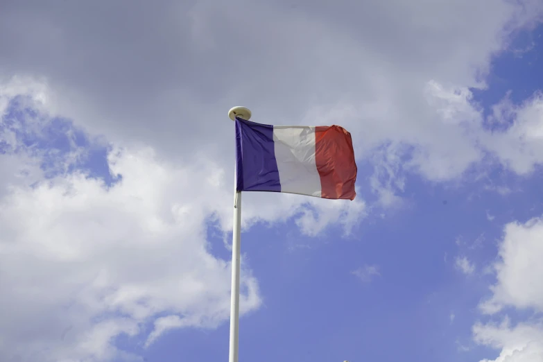 the french flag is fluttering on a very cloudy day