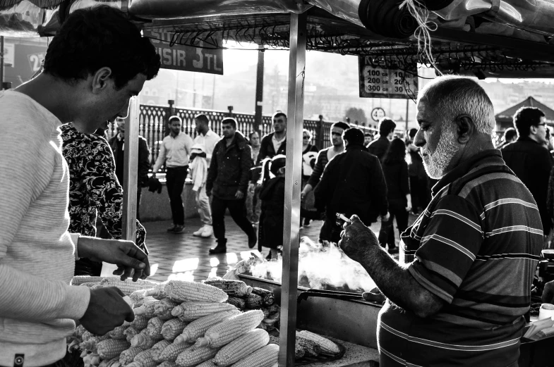 a man standing near another man and selling food