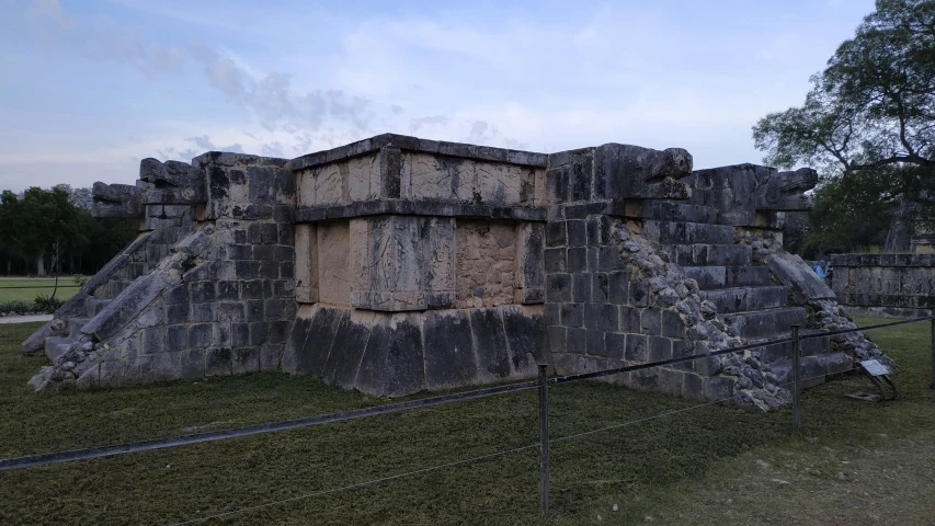 a stone structure with lots of walls is next to a fence