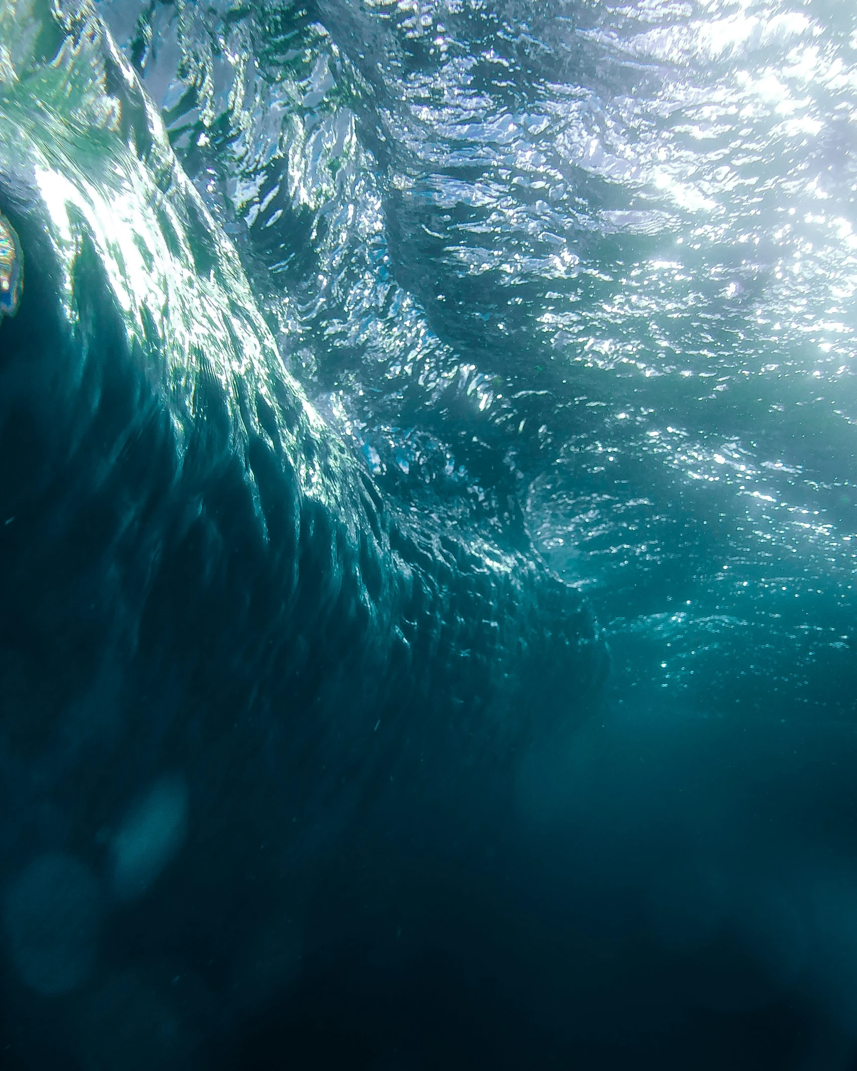 water is swirling up around a wave under bright sun