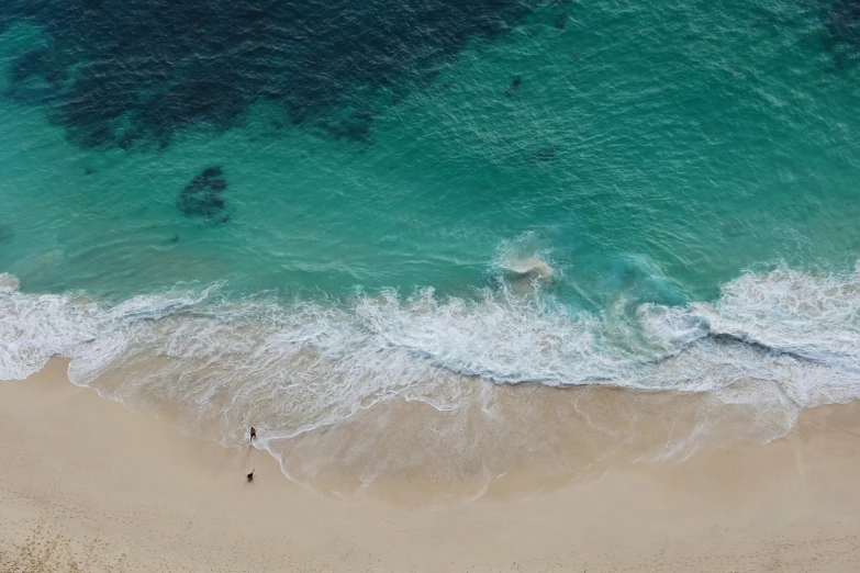 aerial view of waves hitting the beach and people