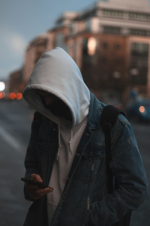 a man wearing a hood and looking at his cell phone