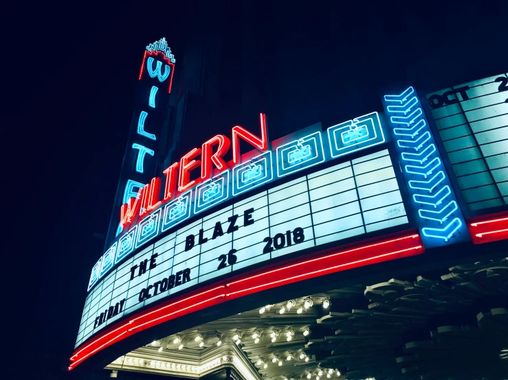 a theater marquee with lit up signs at night