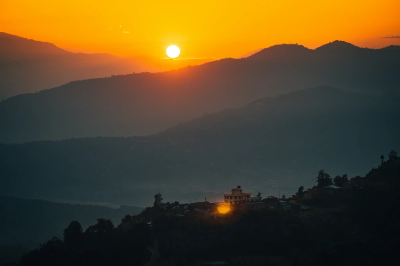 the sun is setting over a forested mountain