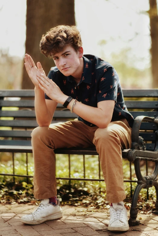 a boy is sitting on a bench in a park