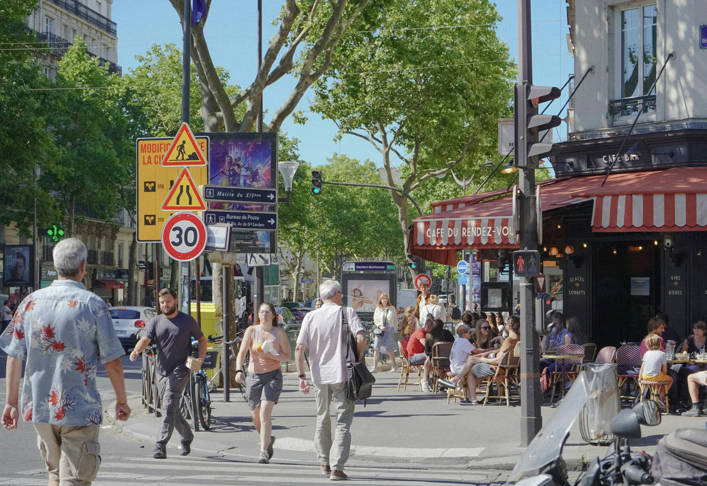 many people walking on the street near a street cafe