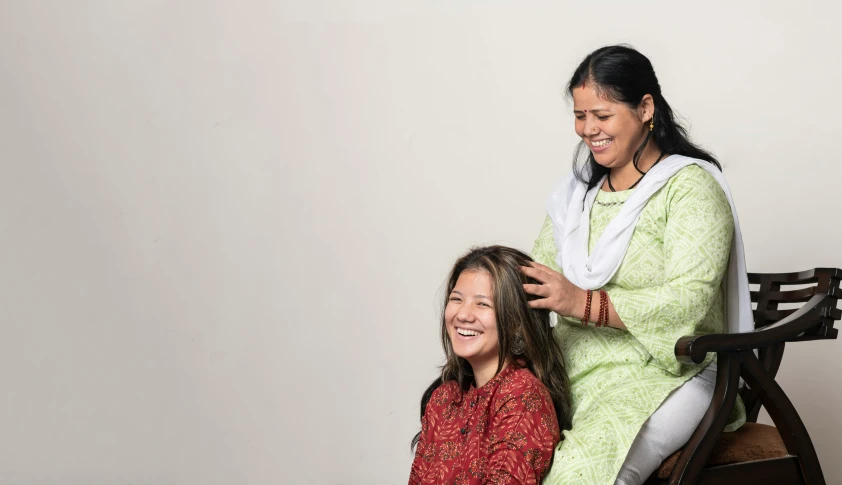 two women sitting on top of a chair together