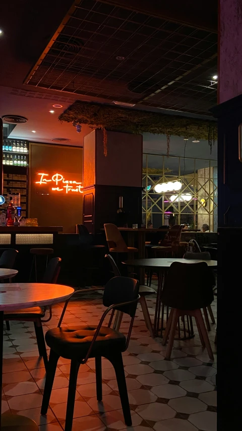 an empty room with chairs, tables and bar lights