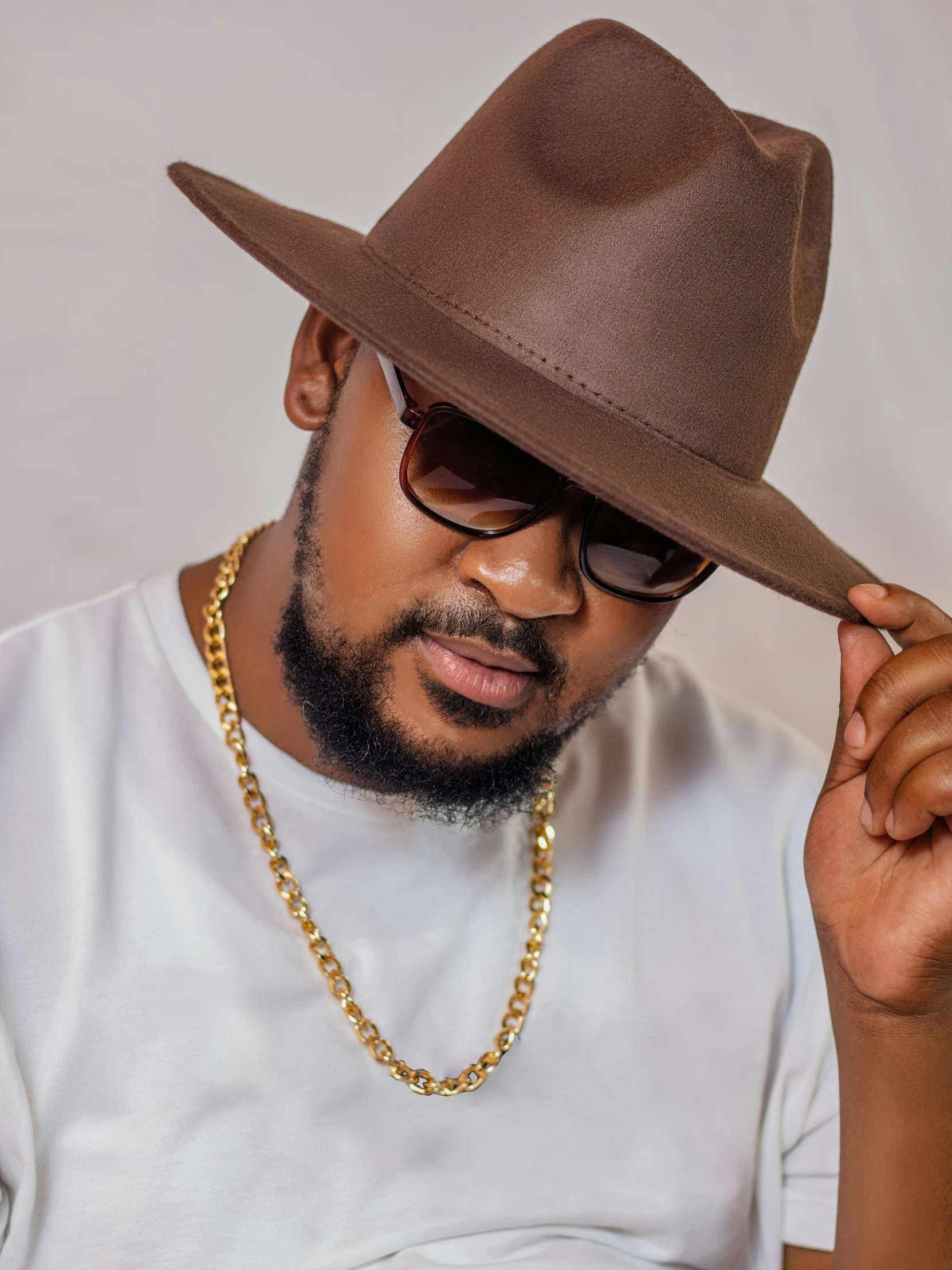 man wearing a tan hat, white shirt and sunglasses