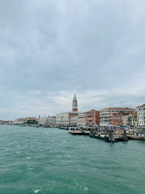 a pier filled with lots of boats under a cloudy sky