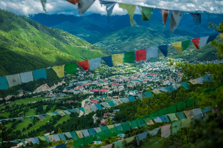 colorful flags hang on a mountain and above some small town