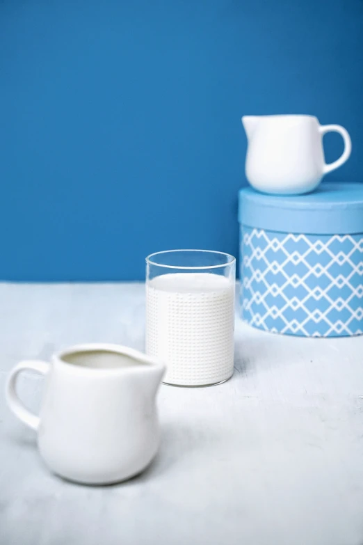 a plain white cup, tea pot, container and glass of water