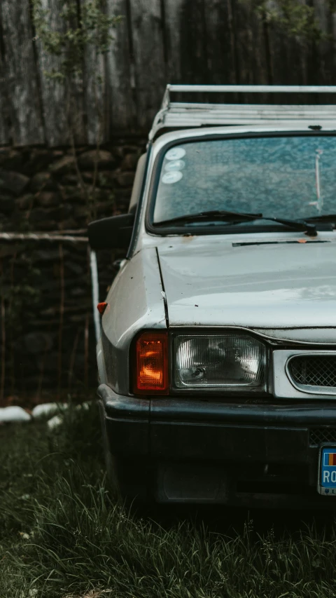 an old car parked in front of a stone wall