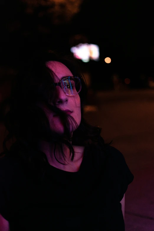 a girl at night with the street lights behind her