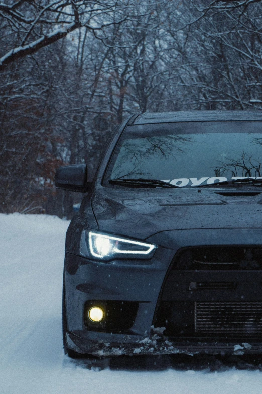 the front end of a black car on a snow covered road