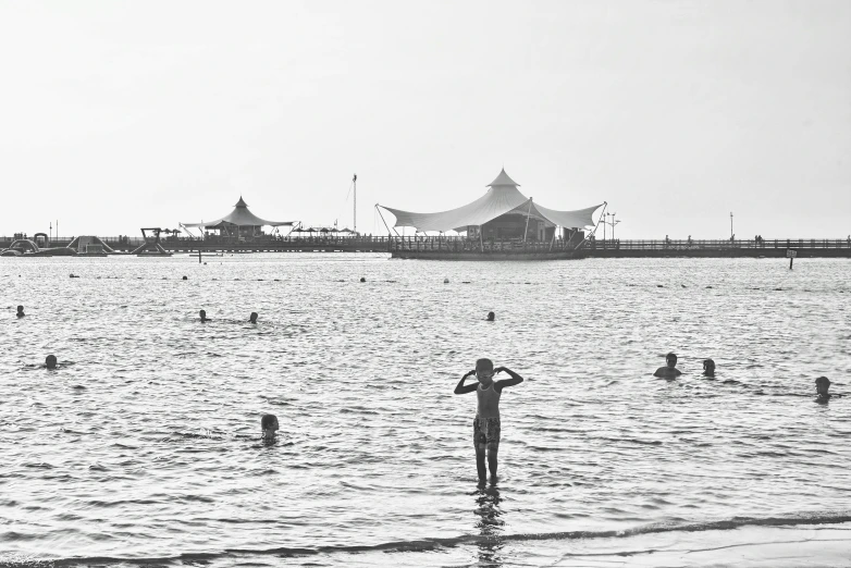 some people are on the beach swimming and standing in the water