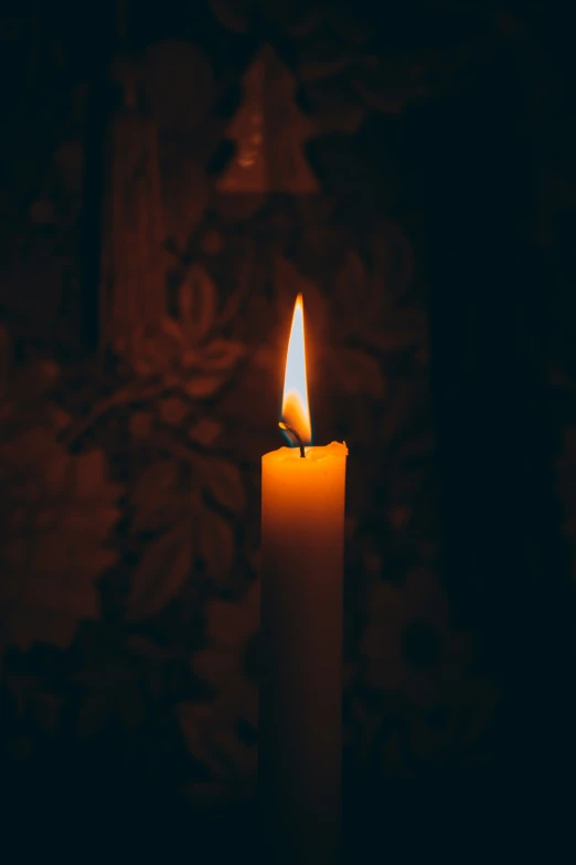 a white candle has lit in a dark room