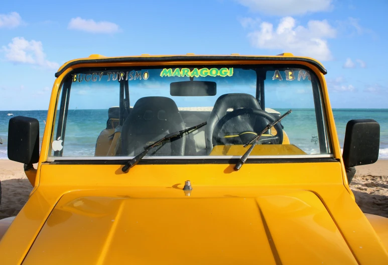 an automobile parked on a beach next to the ocean