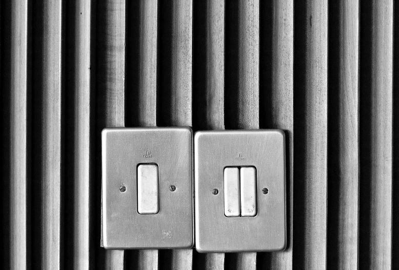 two switches on a wall near several dark stripes
