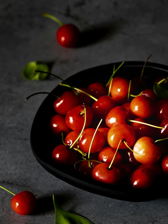 bowl of cherries with one whole cherry next to it