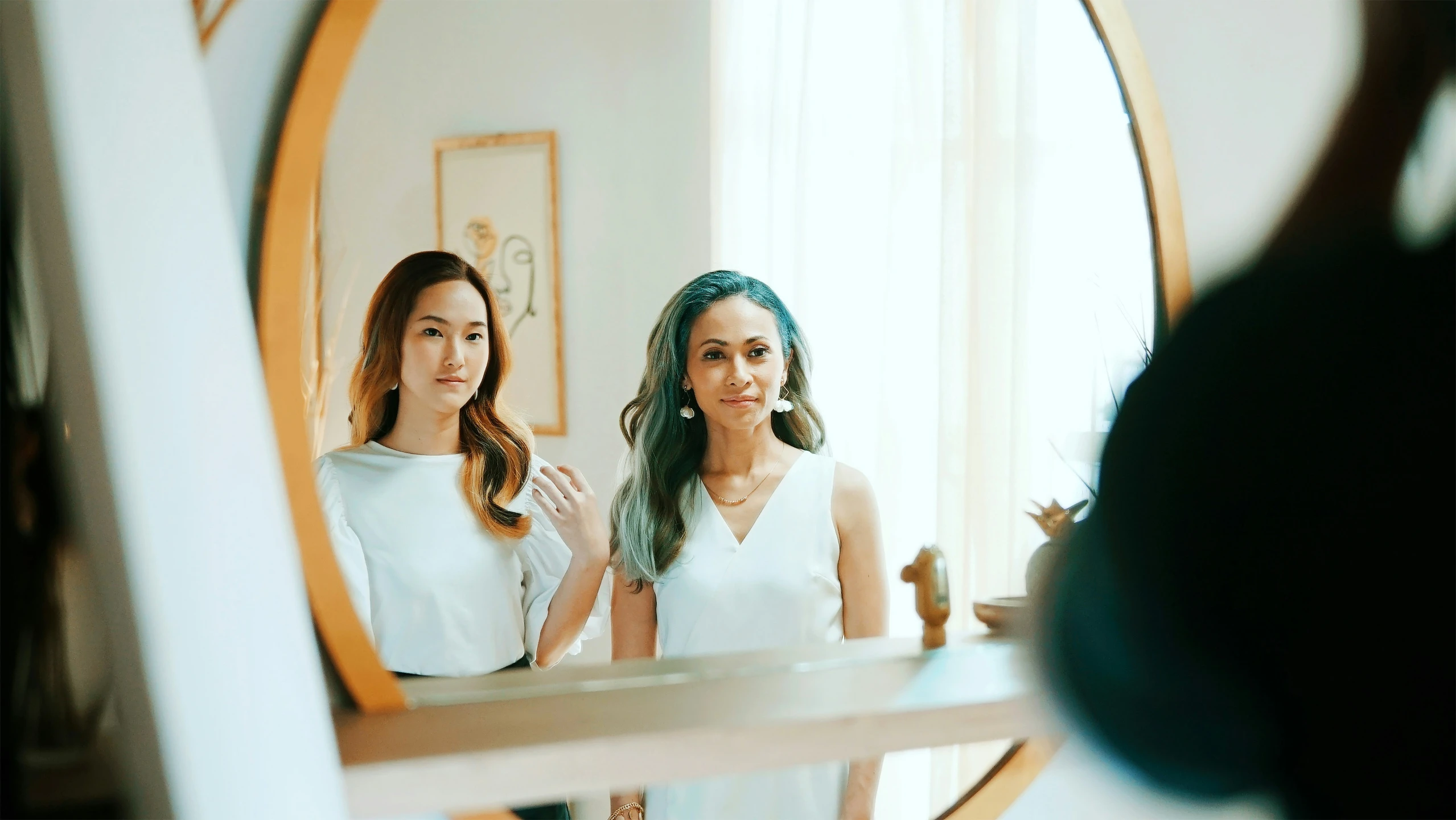 two women in white dresses are looking in the mirror