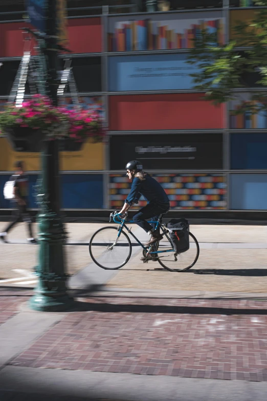 man riding bike on sidewalk near lampposts and building