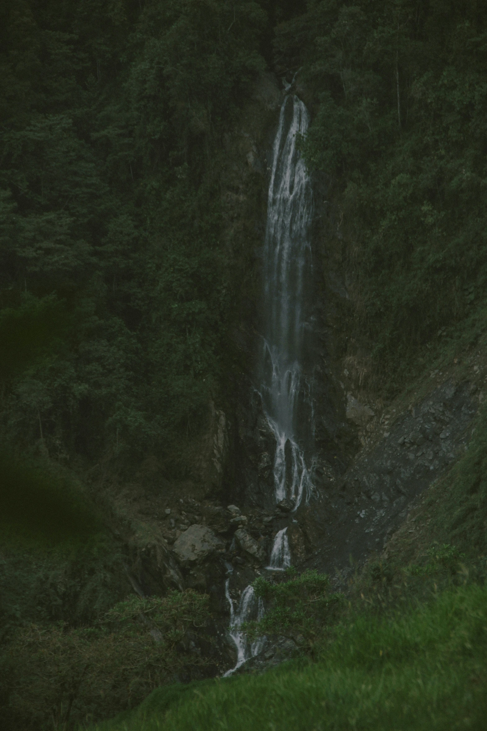 there is a waterfall falling down on the side of a hill