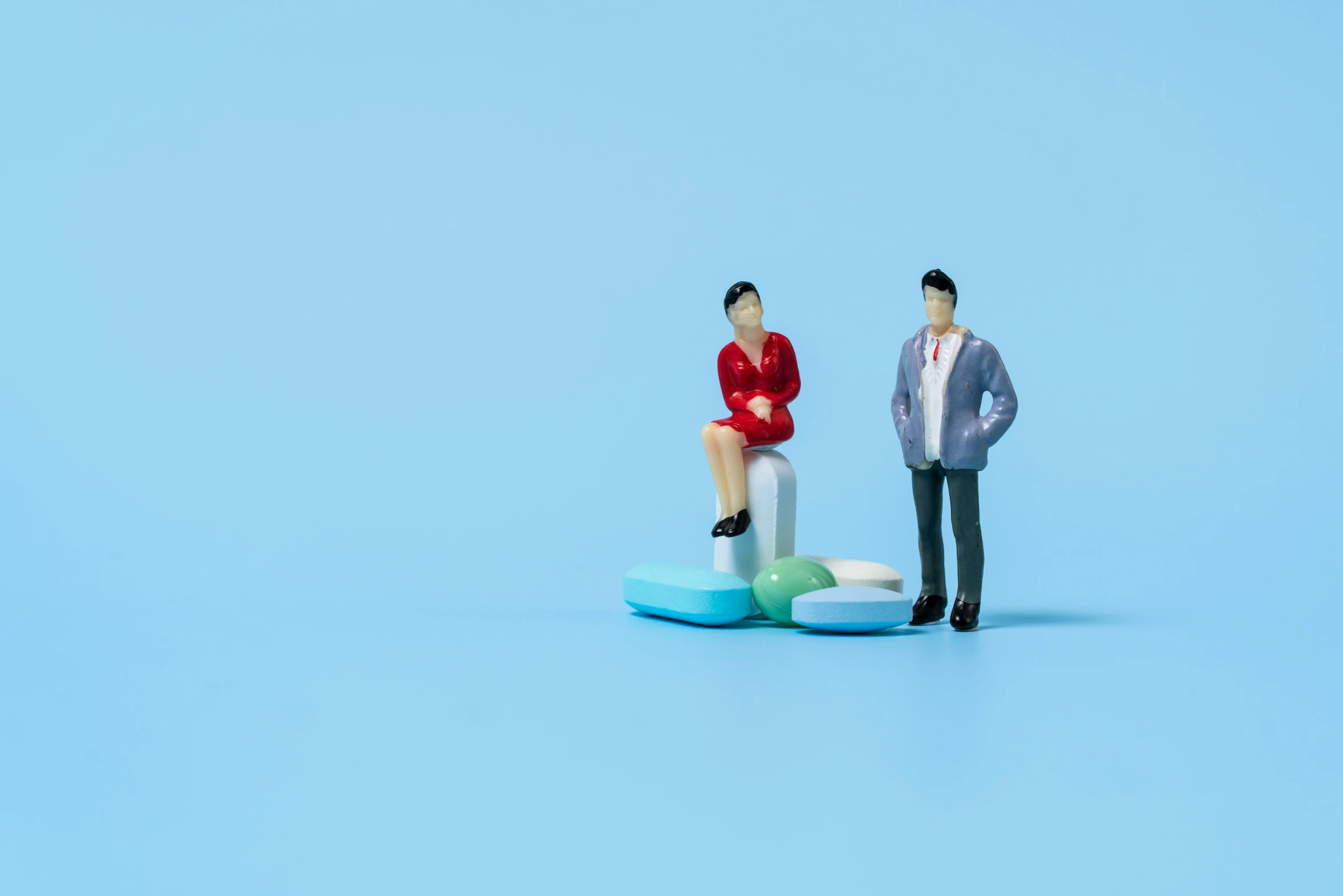two figurines one with the woman sitting on a table, the other wearing a business suit