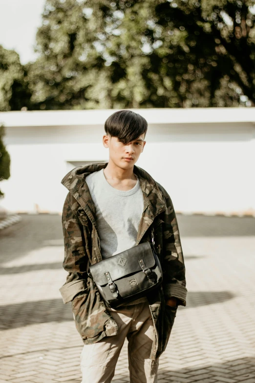 an asian man in a camouflage coat carrying a black purse