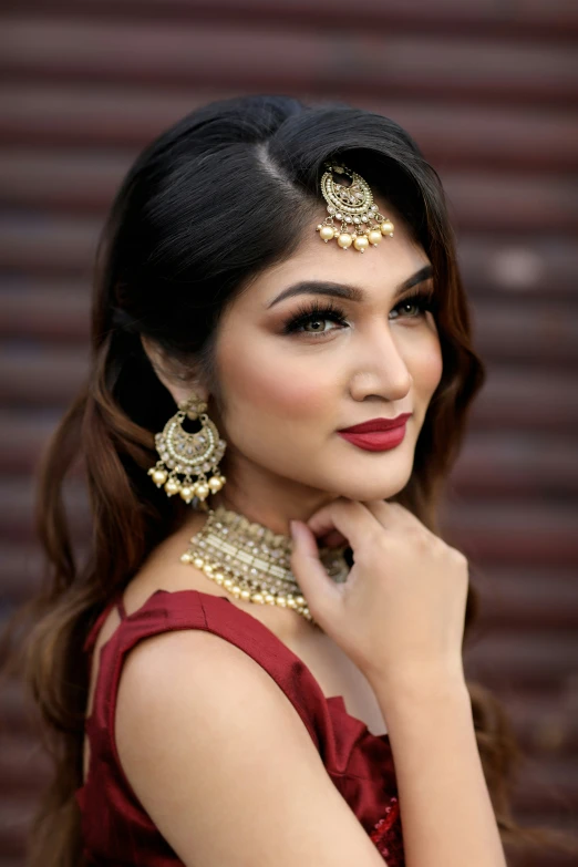 young woman wearing jewelry in her hair standing against a brick wall