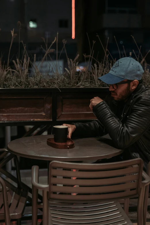 a man sits at a table and looks down on his hand