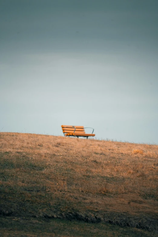 an empty bench that is sitting on a hill