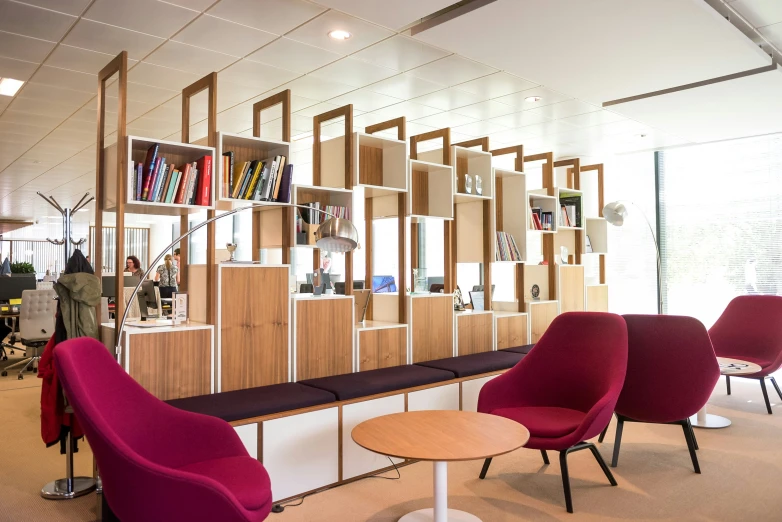 three red chairs in a lounge area with bookcases