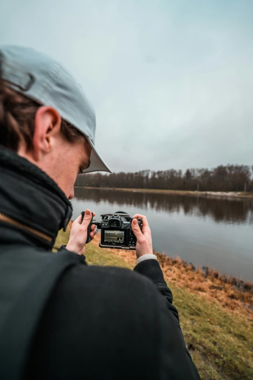 a man holding a camera in front of a lake