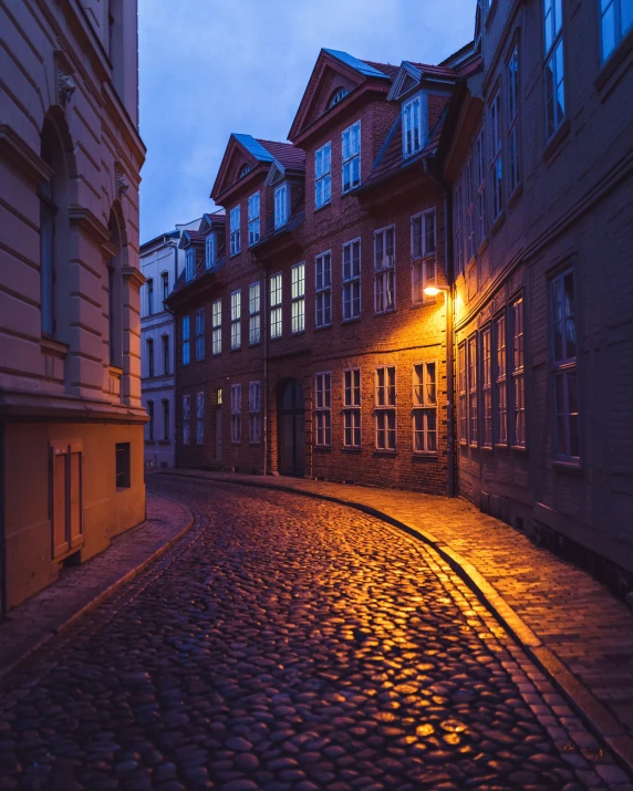 a cobblestone road leads to some tall buildings