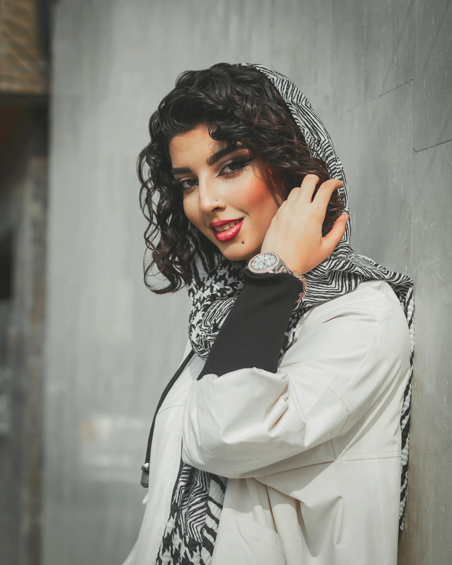 the woman is posing in front of the cement wall