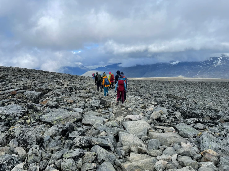 a group of young people are walking along the rocky terrain